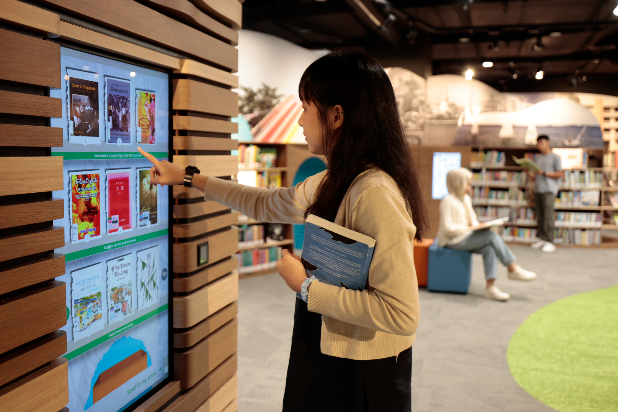 A photo of SG alcove space, a patron is trying out the book recommendation interactive kiosk